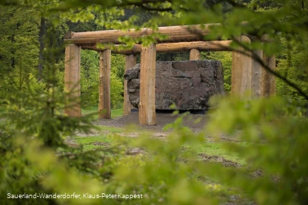 Blick durch eine grüne Blätterwand auf den großen Stein