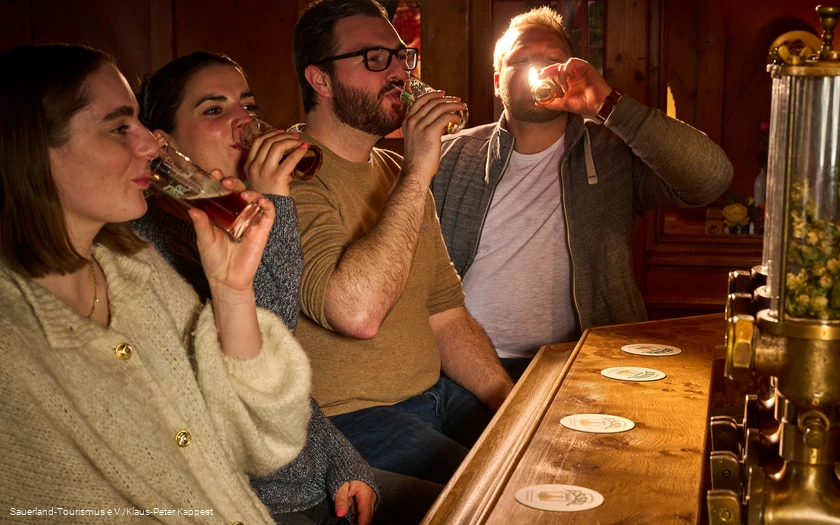 Vier Menschen probieren ein Bier während einer Bierprobe