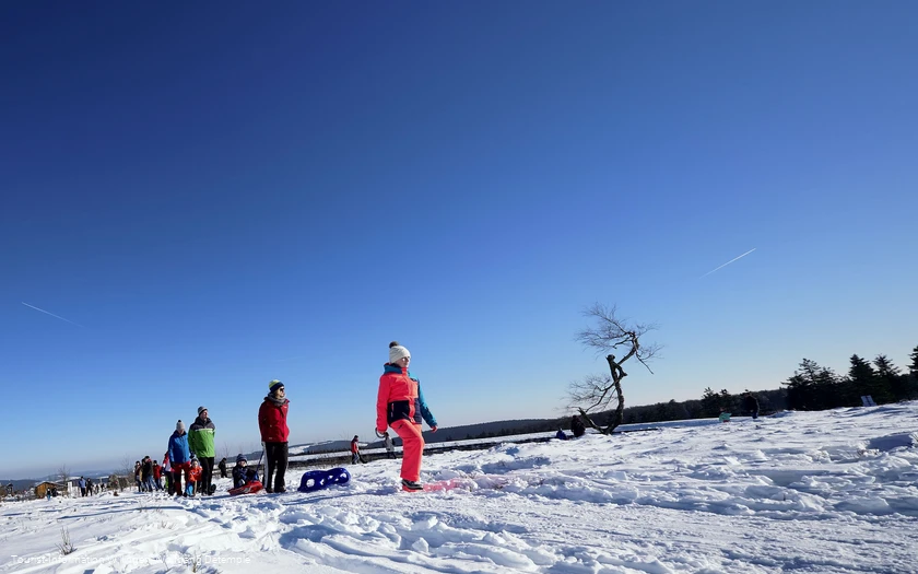 Familie mit Kindern auf Schlitten wandert auf dem Ettelsberg 