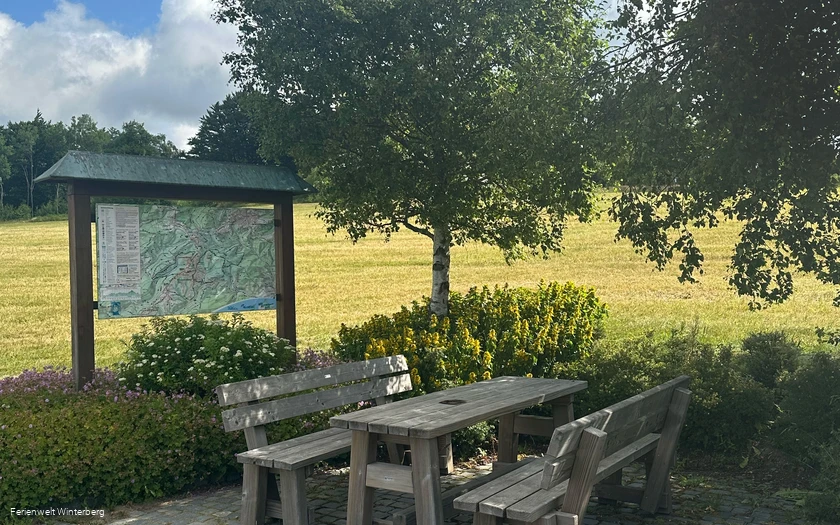 Informationstafel mit Wanderwegen in und um Lenneplätze neben zwei Bänken mit einem Tisch.