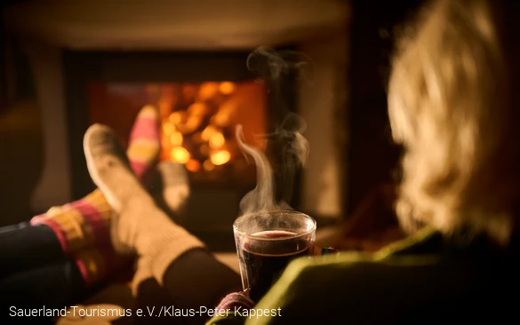 Eine Frau entspannt mit einem heißen Tee vor dem Kamin