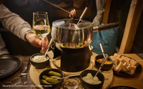 Blick auf ein Fondue mit einem Weinglas
