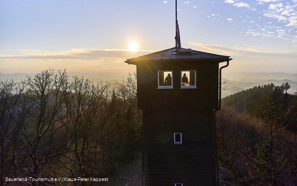 Zwei Wanderer bestaunen die Wintersonne auf dem Wallburgturm