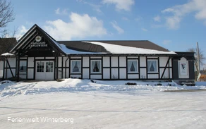 Die Schützenhalle Langewiese mit dem sich davor befindlichen zugeschneiten Parkplatz im Winter.