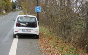 Parkstreifen neben einer Hauptverkehrsstraße mit einem weißen geparkten Auto.