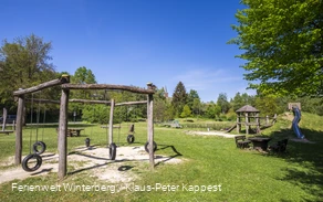 Ein Spielplatz mit Klettergerüst, Rutsche und Schaukeln.