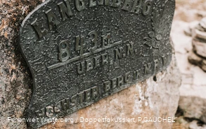 Ein Metallschild an einem großen Stein angebracht mit der Aufschrift Langenberg 843 m über N.N.