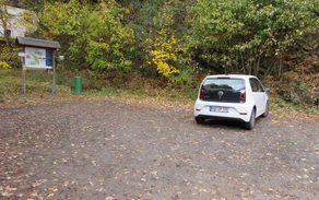 Ein Waldparkplatz mit einem weißen geparkten Auto.