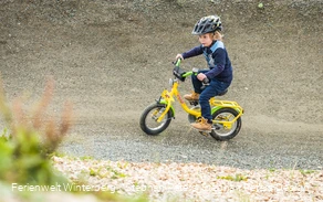 Ein Junge fährt auf seinem Fahrrad über einen Schotterweg.