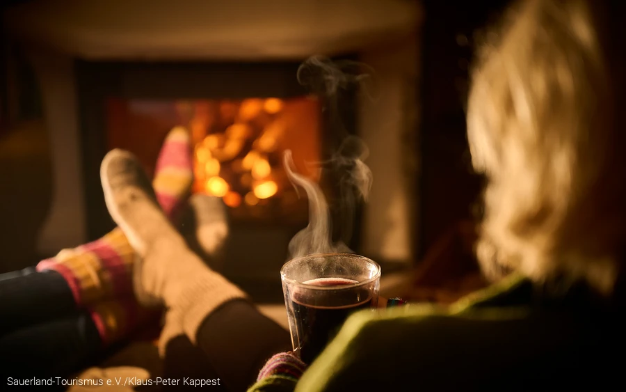 Eine Frau entspannt mit einem heißen Tee vor dem Kamin