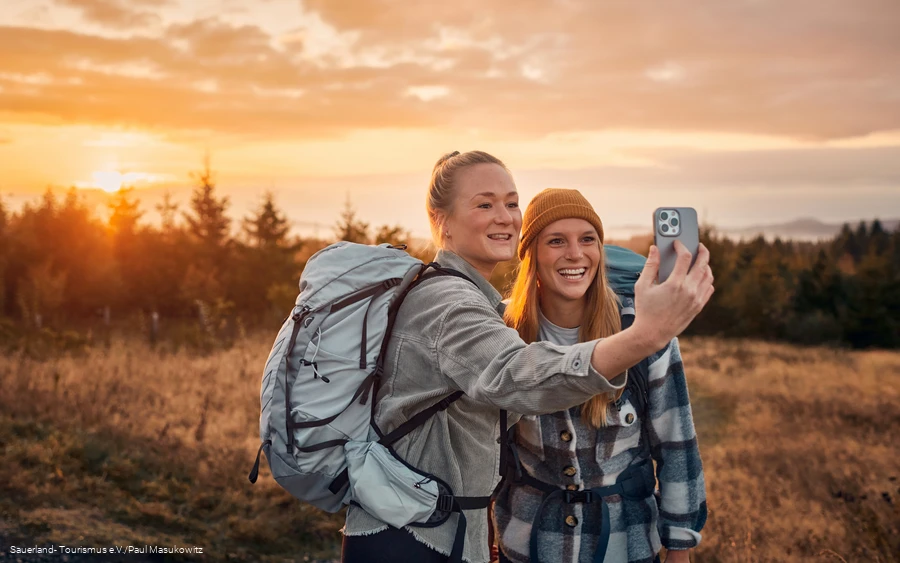 Zwei junge Frauen machen ein Selfie beim Sonnenaufgang auf dem Kahlen Asten