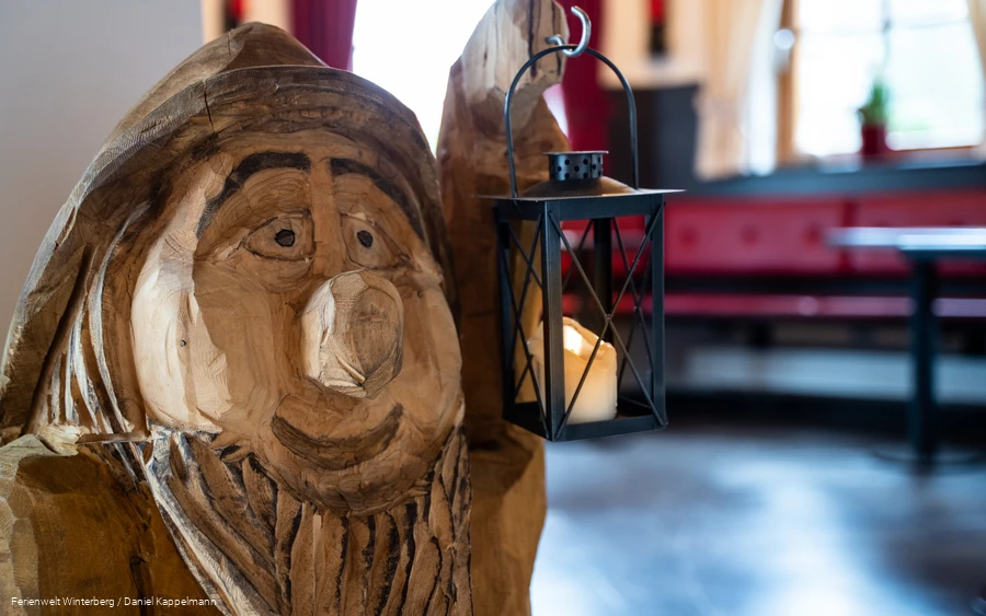Ein aus Holz geschnitzter Zwerg mit einer Laterne in der Hand.