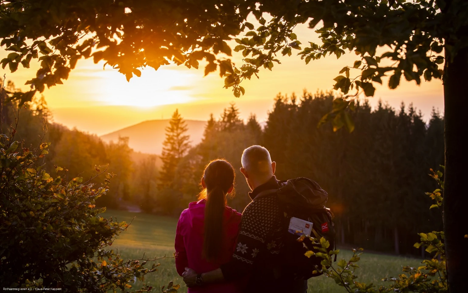 Zwei Rothaarsteig-Wanderer schauen in den Sonnenuntergang auf der Rothaarsteig-spur Sorper Panoramapfad