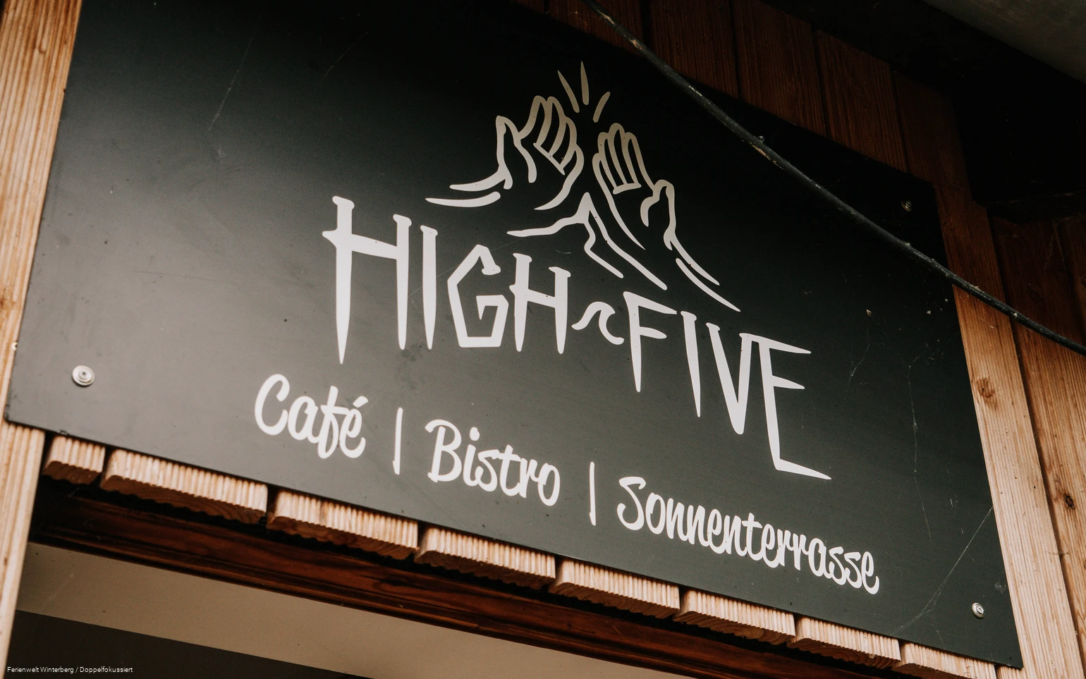 Ein Stück einer Eingangstür mit einem Schild mit der Aufschrift High Five oberhalb der Tür.
