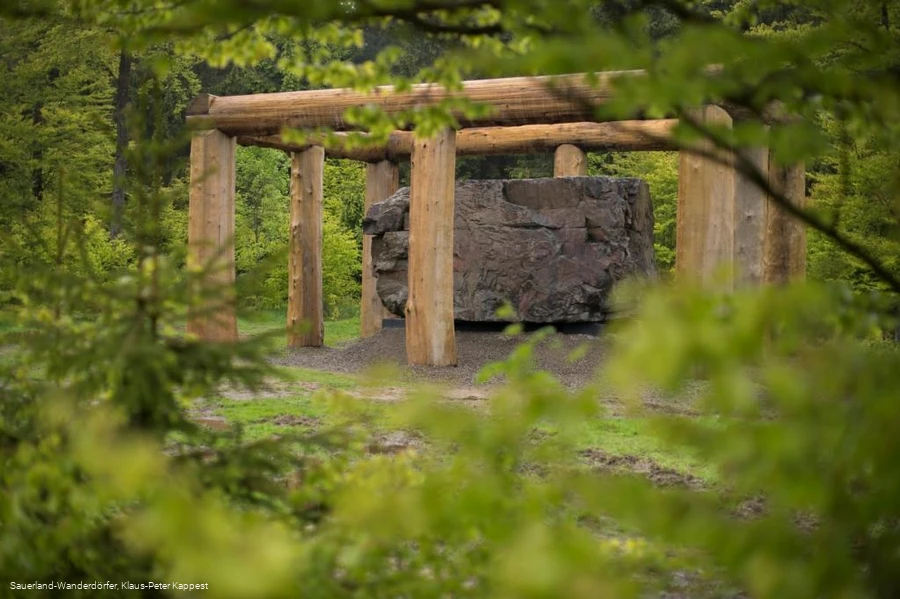 Blick durch eine grüne Blätterwand auf den großen Stein
