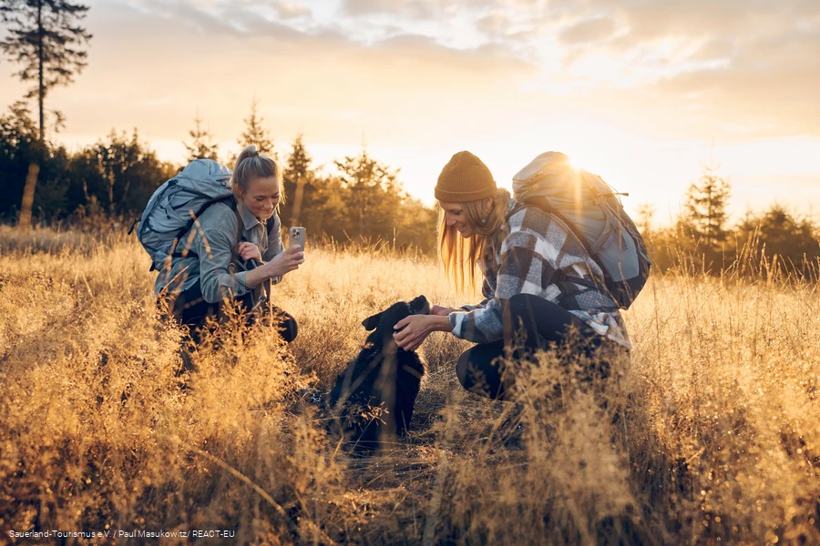 Eine Frau macht ein Handyfoto von einer anderen Frau mit Hund morens auf dem Kahlen Asten