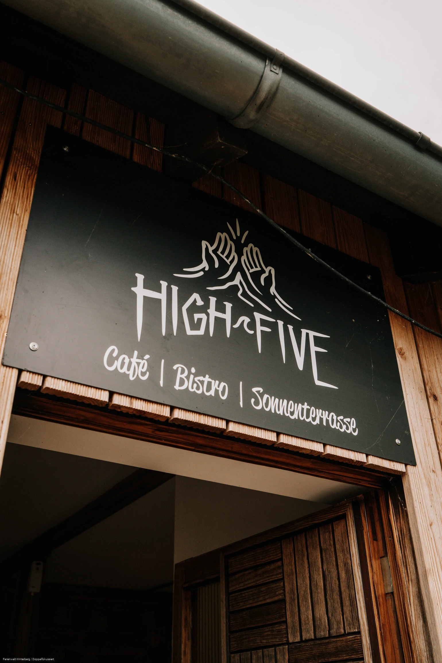 Ein Stück einer Eingangstür mit einem Schild mit der Aufschrift High Five oberhalb der Tür.