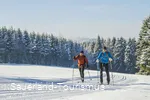 Langläufer-Paar vor verschneiten Tannen