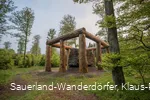 Die Holzstämme umringen den Stein der Stein-Zeit-Mensch Skulptur