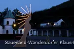 Museum von außen bei Nacht mit einer künstlerisch beleuchteten Holzfigur im Vordergrund