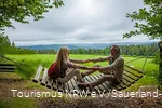 Eine Frau und ein Mann sitzen sich auf einer großen Schaukel gegenüber