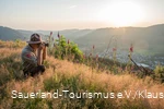 Ein Ranger sitzt am Rothaarkamm im Gras und fotografiert