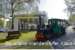 Menschen sitzen in einer fahrenden grünen Lok auf dem Museumsgelände