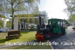Menschen sitzen in einer fahrenden grünen Lok auf dem Museumsgelände