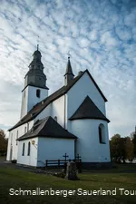 Rückseite der Kirche in Wormbach vor leicht bewölktem Himmel