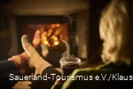 Eine Frau genießt mit einer heißen tasse Tee den Winterbane dvor dem Kamin