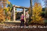 Tourführung rund um den Wald-Skulpturen-Weg mit Fokus auf die Stein-Zeit-Mensch Skulptur vor blauem Himmel
